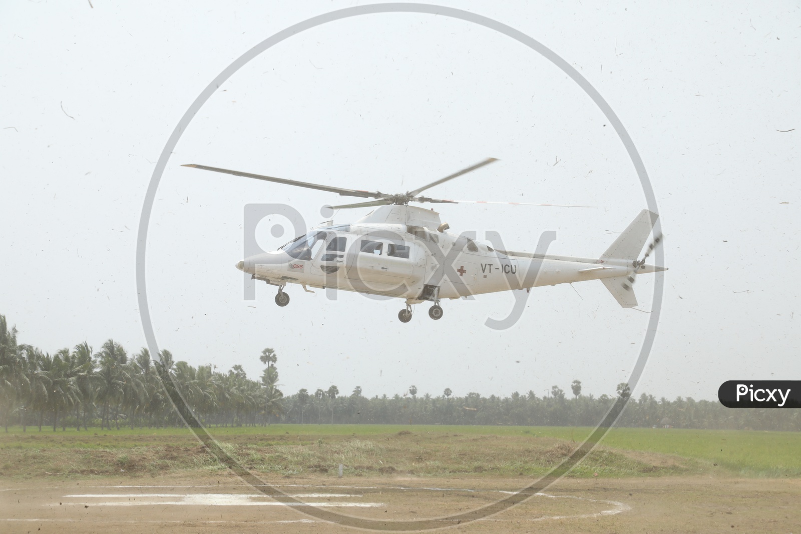 A Helicopter Landing on Helipad with Agriculture Fields in Background