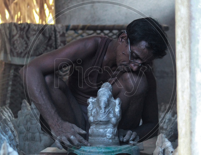 Man fixing the defaults in an eco friendly ganesh idol.