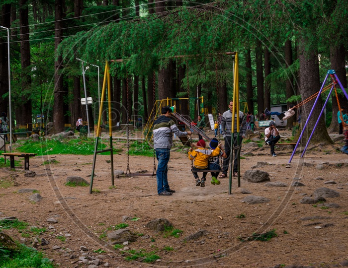 Indian Father with his Kids Playing on Swing in Van Vihar National Park at Manali