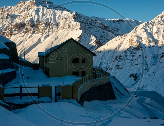 A House Covered in Snow with Snowy Himalayan Mountains in Background