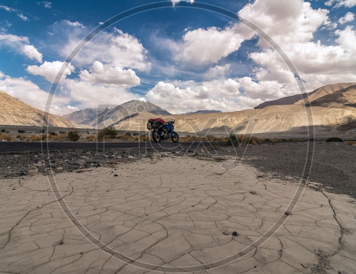 A Traveler's bike parked amidst the high passes of Ladakh mountains