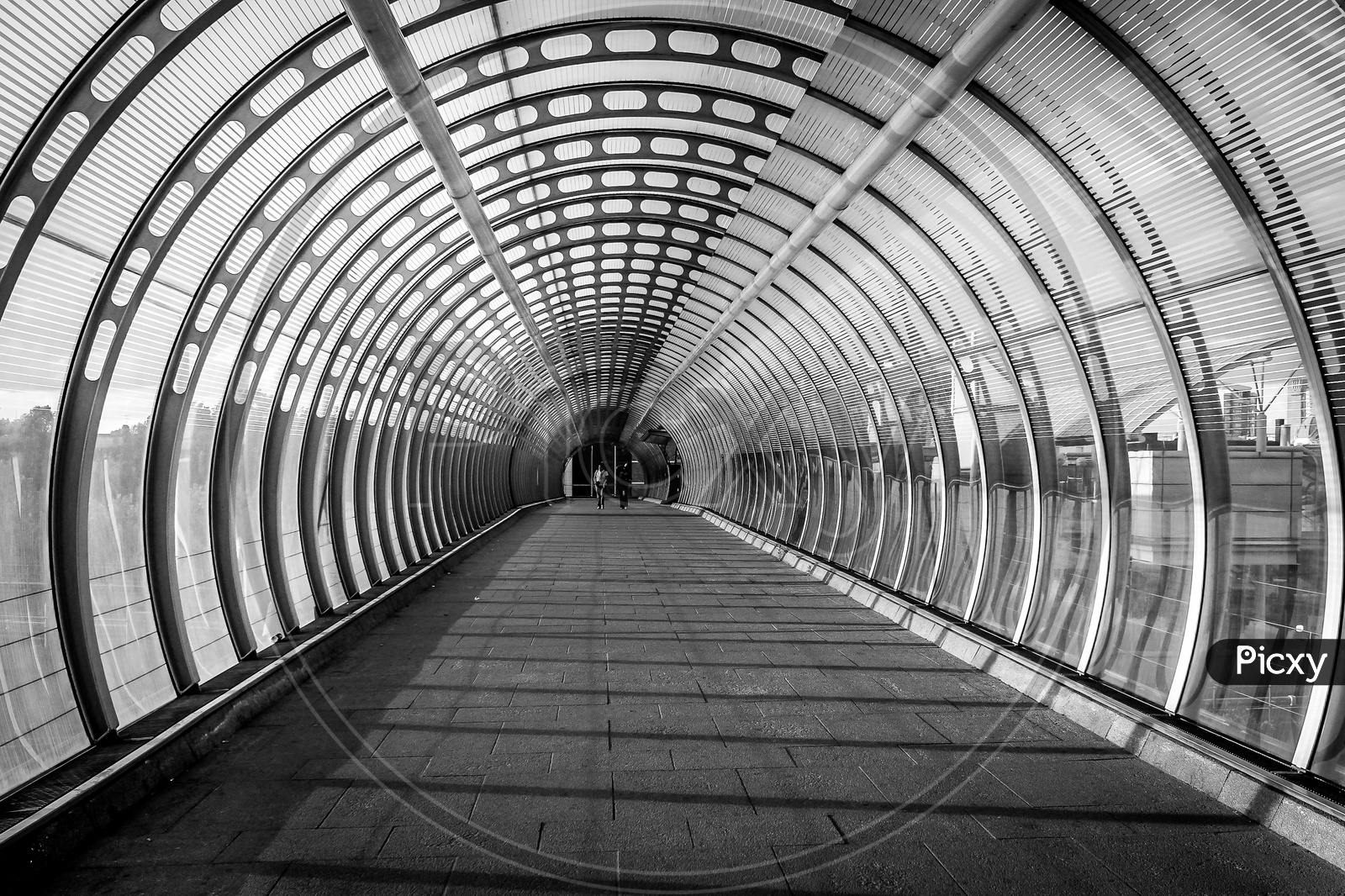 Vortex like Pedestrian bridge built with glass and steel and two women friends walking down during evening sunset of summer in canary wharf of London
