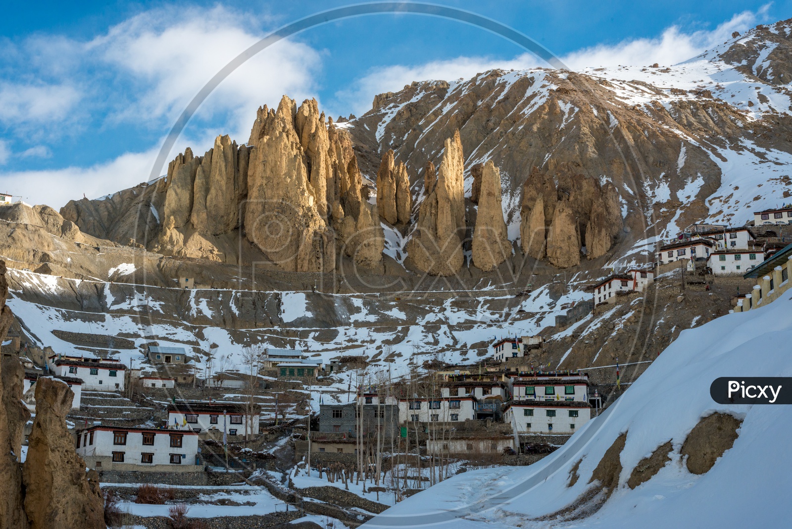 A Village on Mountain Covered in Snow with Rock Mountains in Background