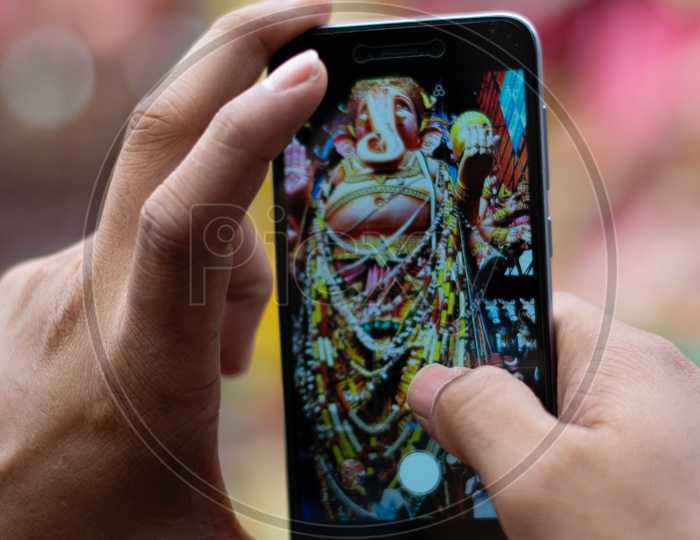 A Devotee taking Picture of Khairatabad Ganesh Idol on Mobile or Smartphone