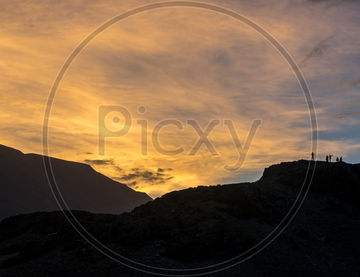 Silhouette of Tourists on top of a mountain range during sunset