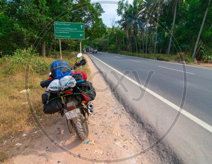 A Traveler's bike parked alongside the road at Tiruvananthapuram highway 
