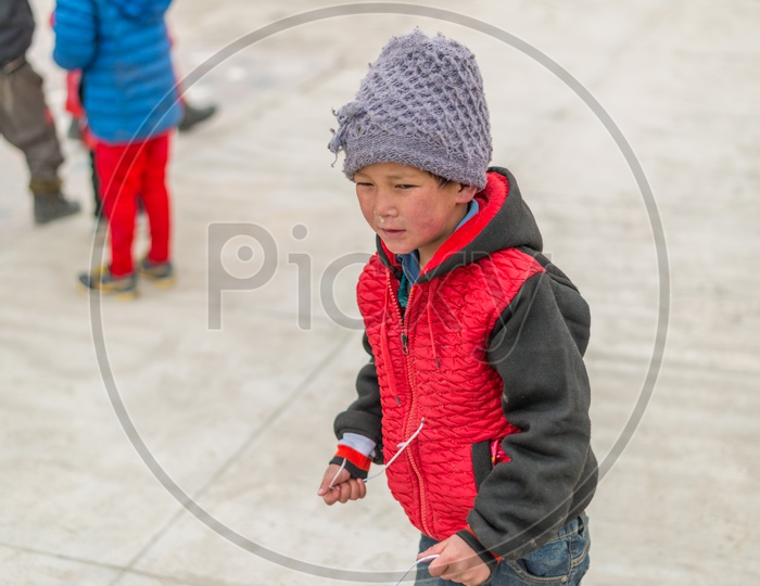 A Kid with Red Jerkin or Jacket in Winter at Monastery playing