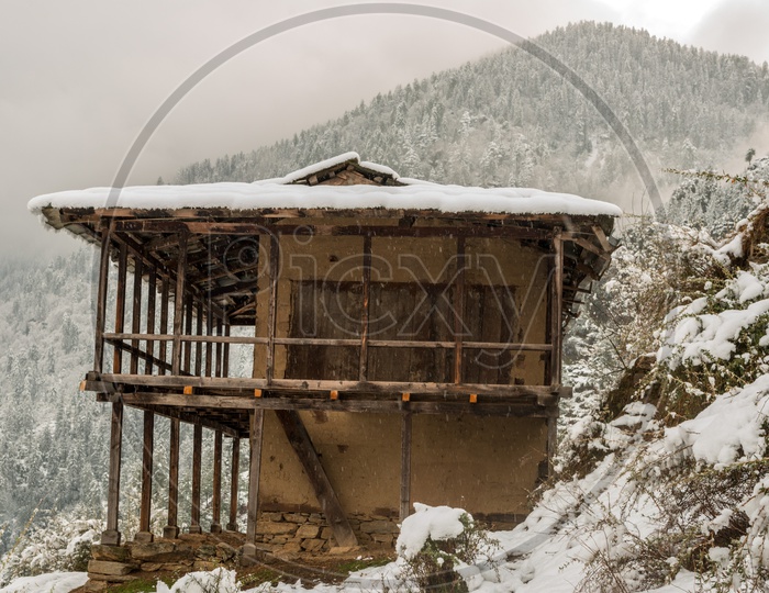 Wooden Houses of Himachal Pradesh Covered with Snow in Winter with Mountains in Background