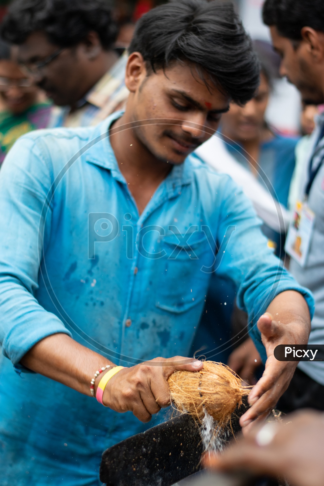Indian Male Devotee breaking Coconut in a Hindu Temple