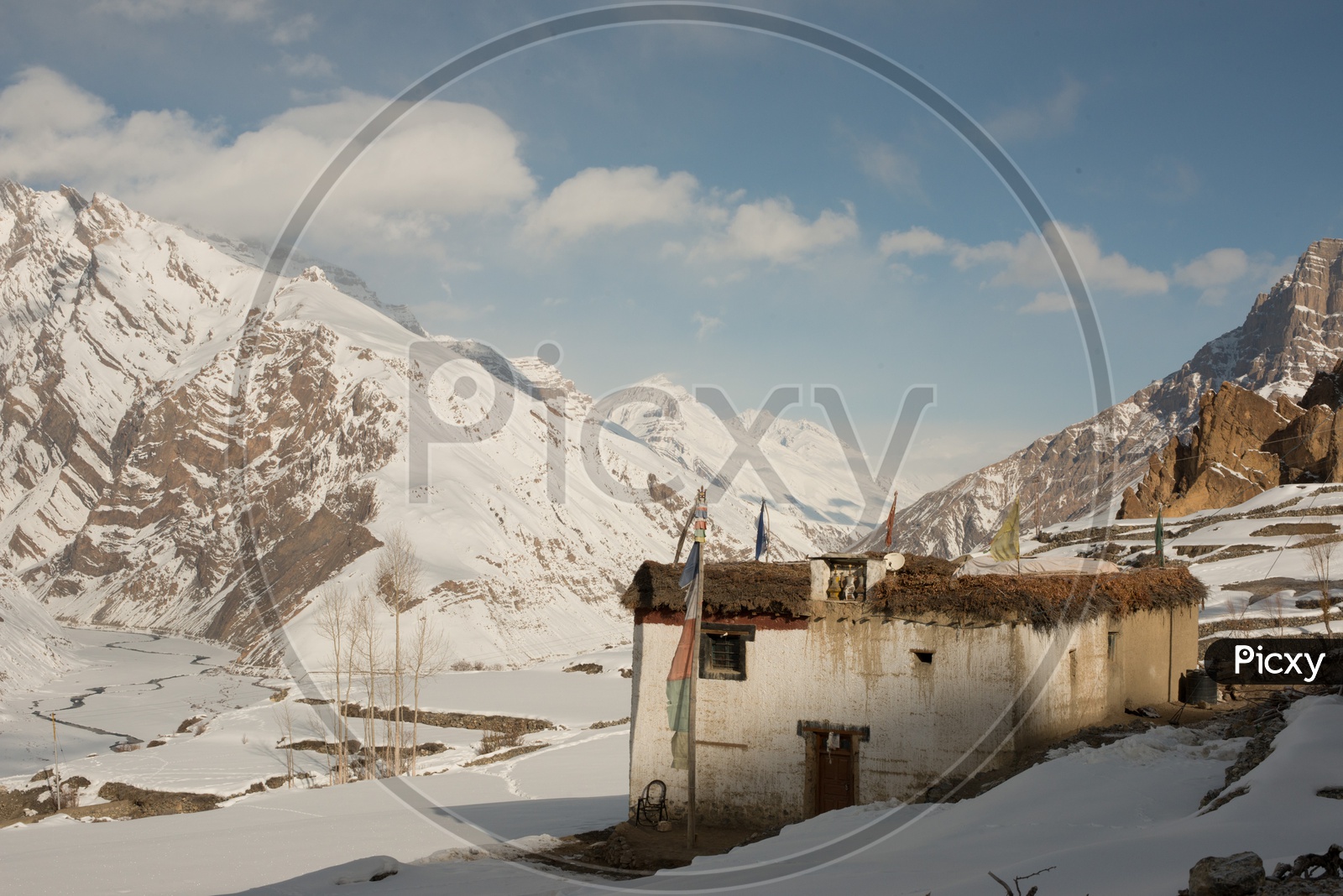 A Small House in Rural Village with Snow Capped Mountains in Background
