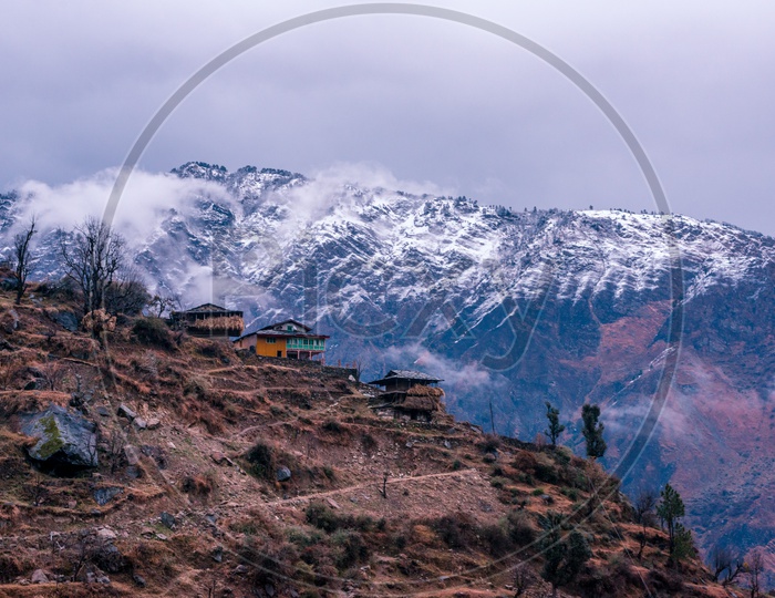 Houses on Mountain Top with Snow Capped Himalayan Mountains in Background