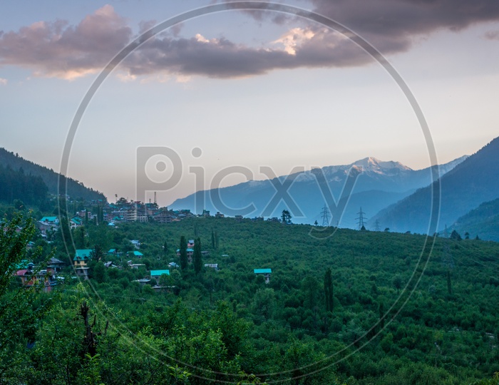 A Small Village Surrounded by Trees with Mountains in Background