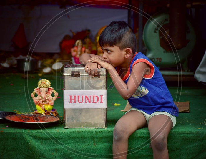 Young Child Siting at Mandapas Or Pandals With Hundi