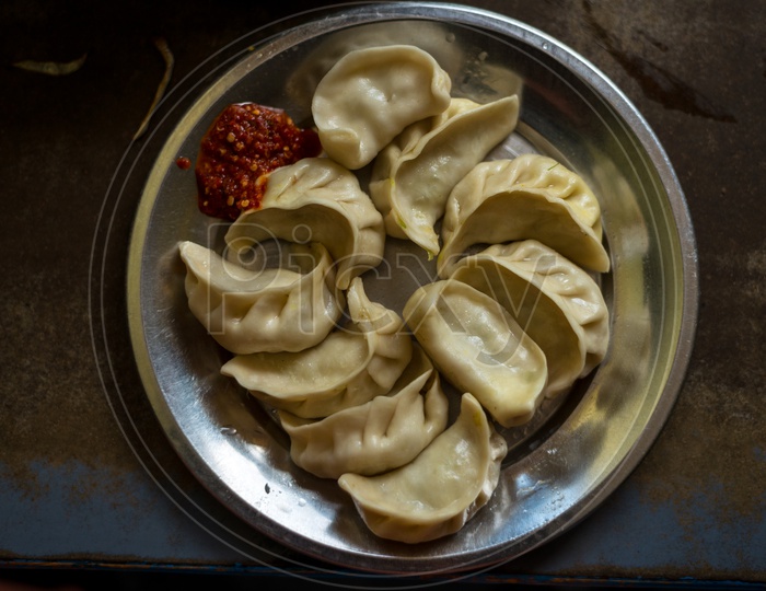 Nepalese traditional dumpling momos steamed served with tomato chutney, schezwan sauce