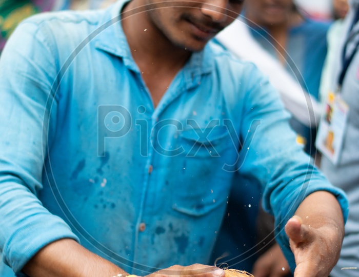 Indian Male Devotee breaking Coconut in a Hindu Temple