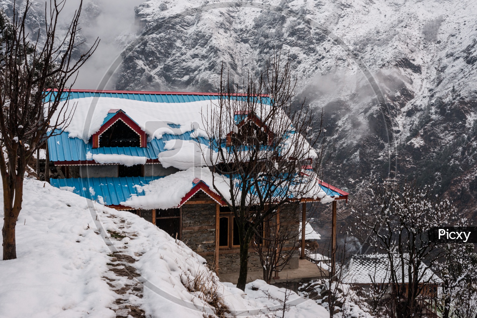 A Wooden House covered with Snow and Snow caped mountain range in Background