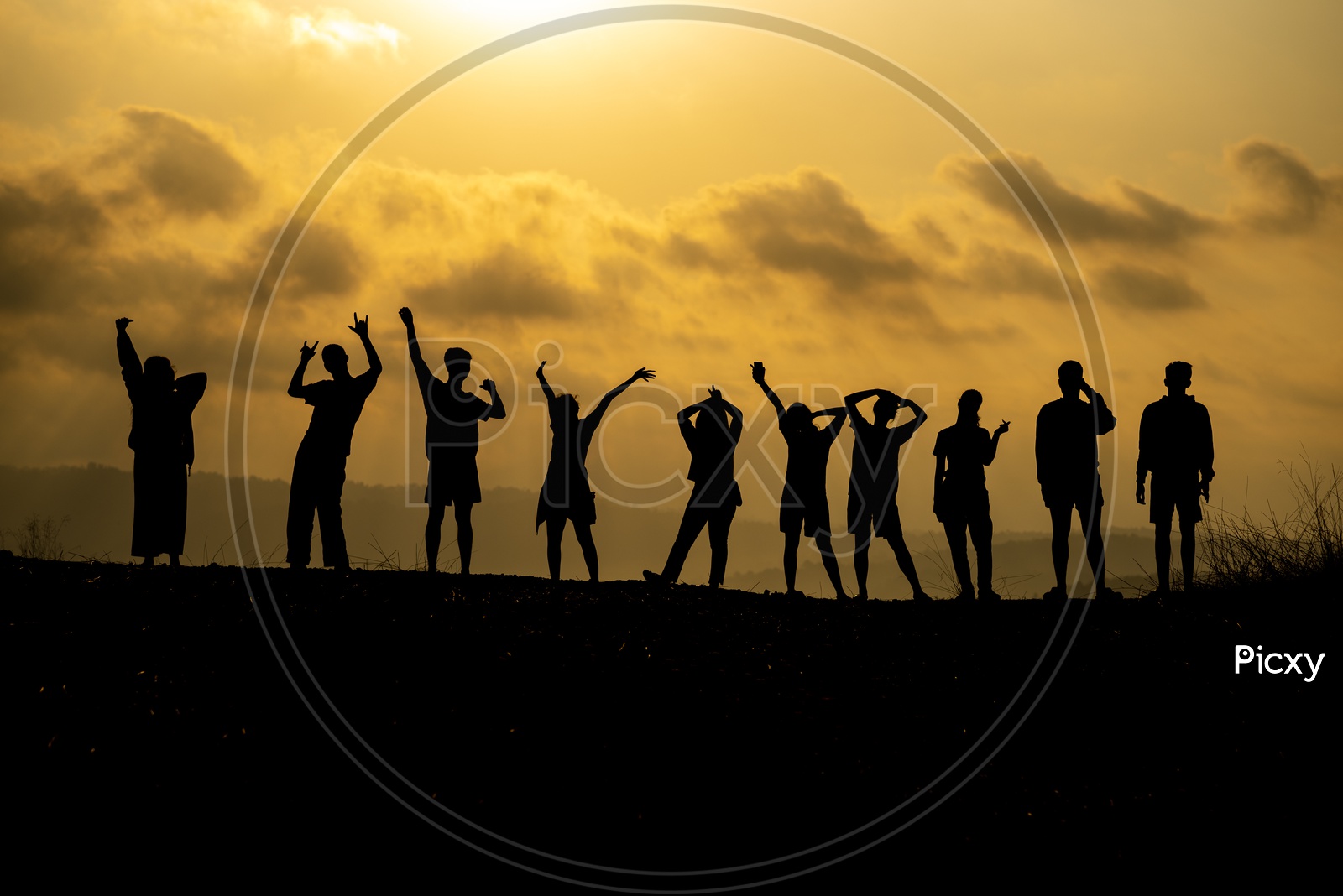 silhouette of  group of people is celebrating success on the hilltop Over Sunset Sky In Background