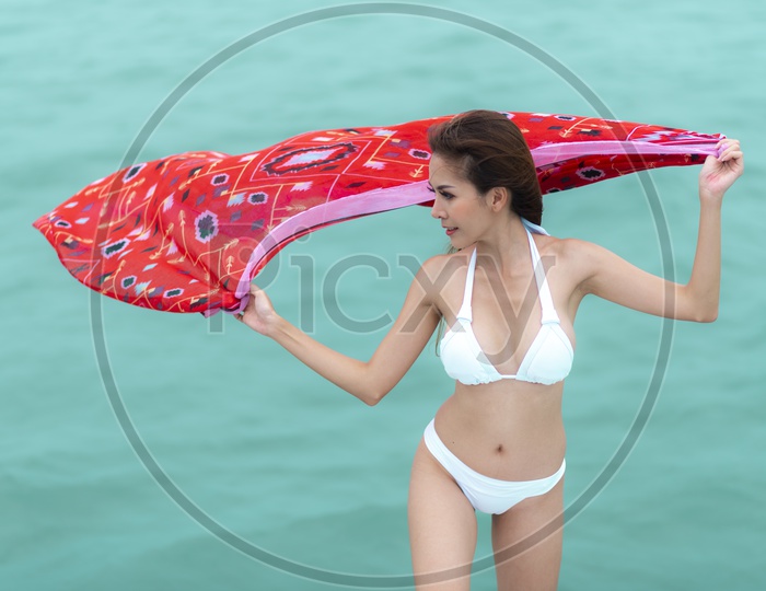 A fashion photoshoot of sexy girl in luxurious bikini holding the scarf