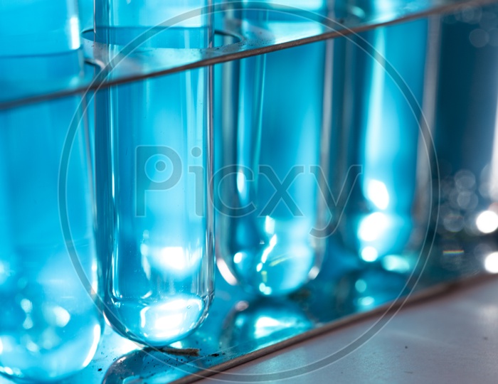 Researchers using glassware and blue solutions in laboratories