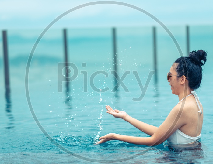 An Asian girl playing with water in Swimming pool on roof top with beautiful city view