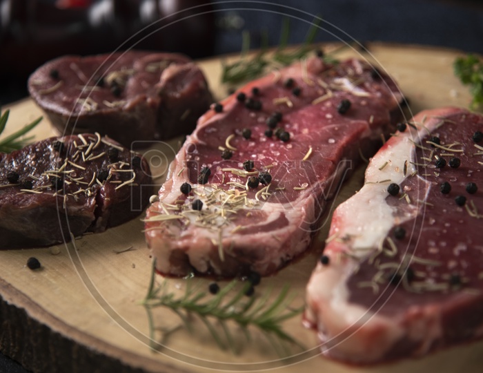 Fresh Raw Beef Steaks Or Red Meat on Wooden Cutting Board With Spices Topped  Closeup