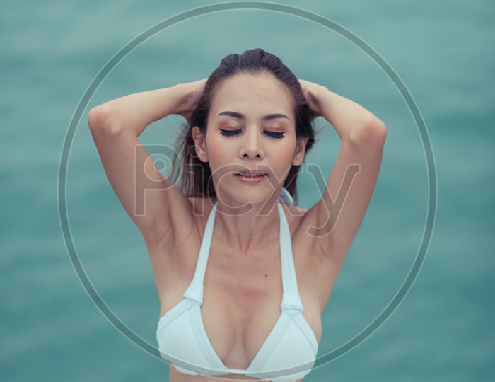 A fashion outdoor shoot of an Asian girl in luxurious bikini by the pool