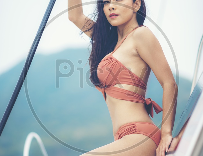 A fashion summer photoshoot of a model in luxurious nude bikini on a Yacht