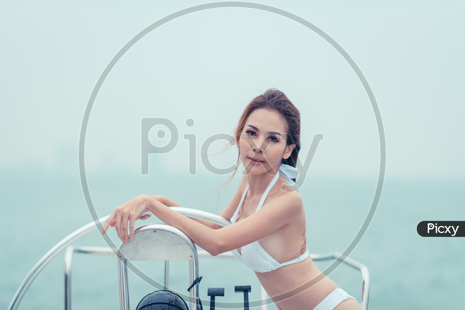 Asian sexy girl with dark hair in luxurious white bikini posing on a Yacht