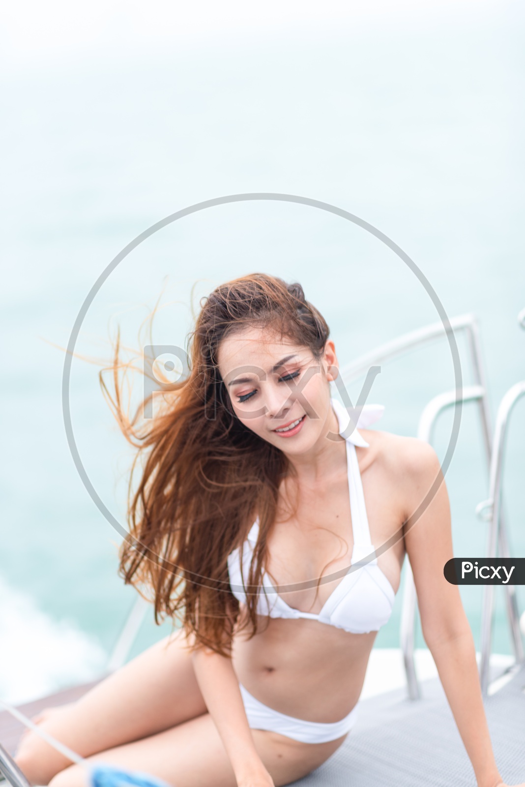 Sexy Asian girl in bikini with loose hair on a yacht