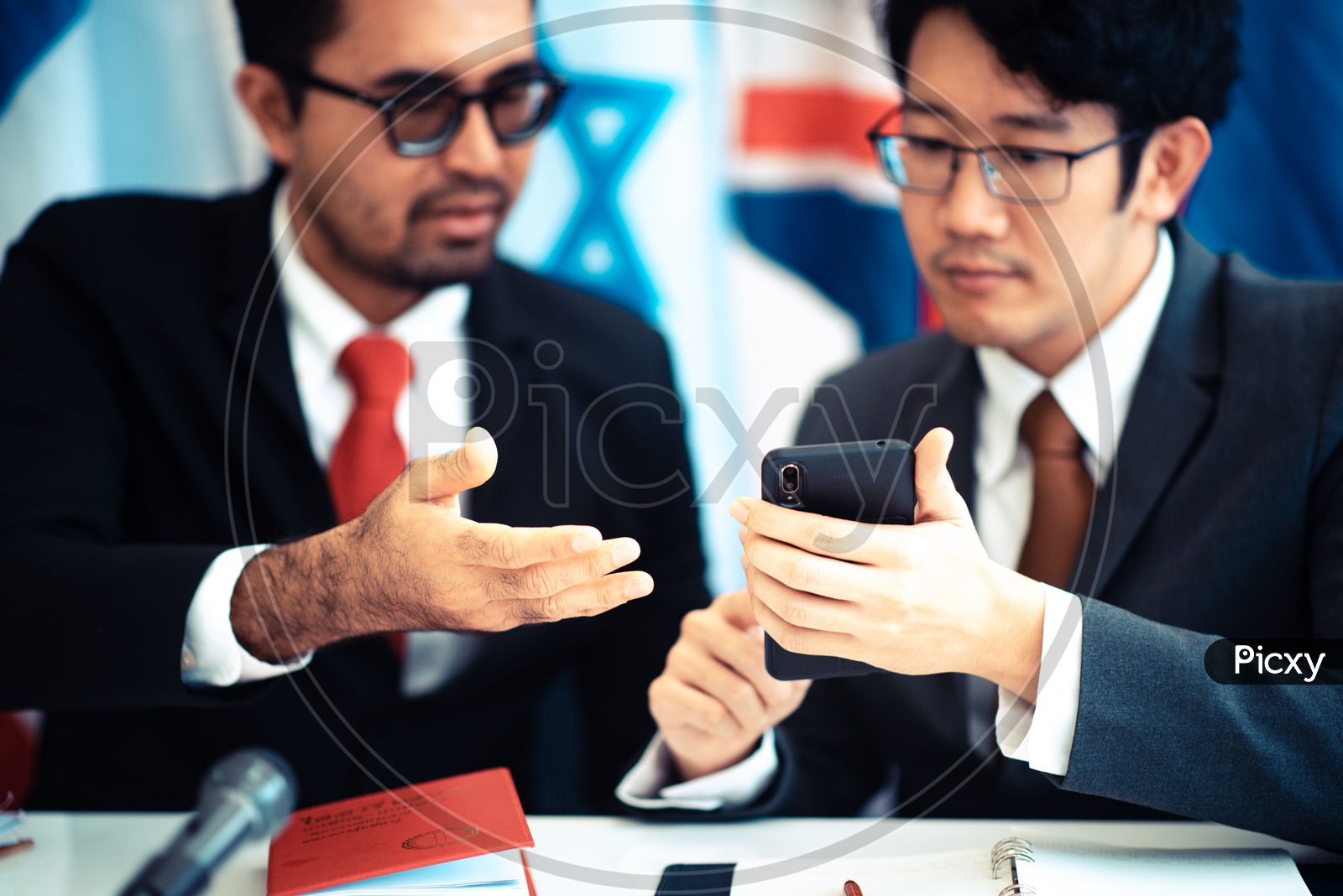 Businessmen using a smartphone during a press conference
