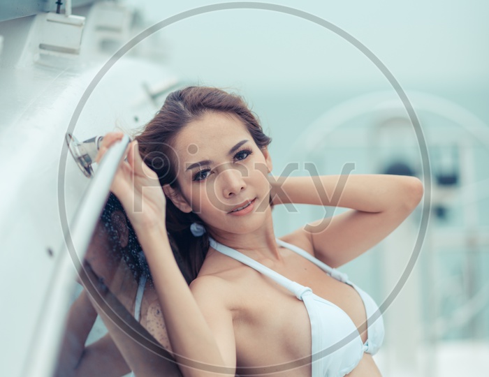 An outdoor shoot of Asian girl with dark hair in luxurious bikini relaxing on yacht