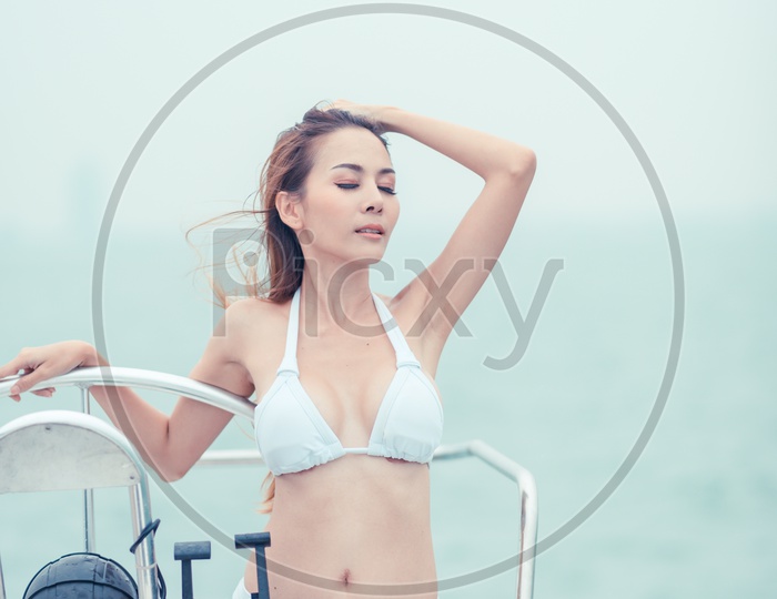 Asian sexy girl with dark hair in luxurious bikini relaxing on yacht
