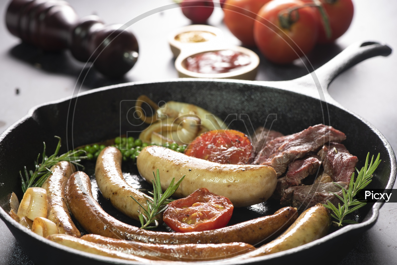 Grilled sausages with Thyme  and tomato ketchup on black Cooking Pan Background