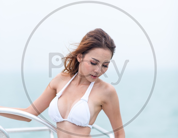 Sexy Asian girl in luxurious white bikini on a yacht