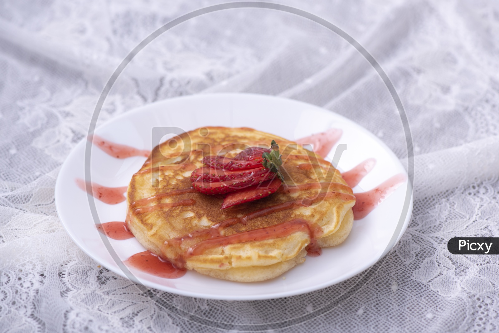 Pancakes with berries and maple syrup served in a plate