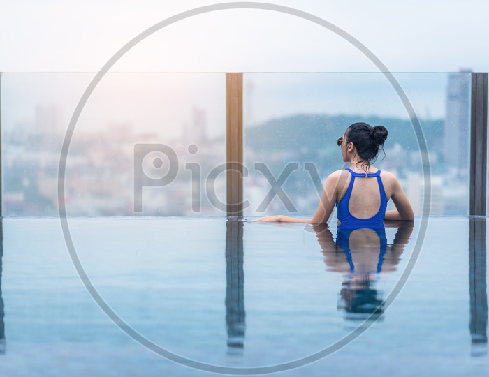 A Model at Swimming pool on roof top with beautiful city and sea view
