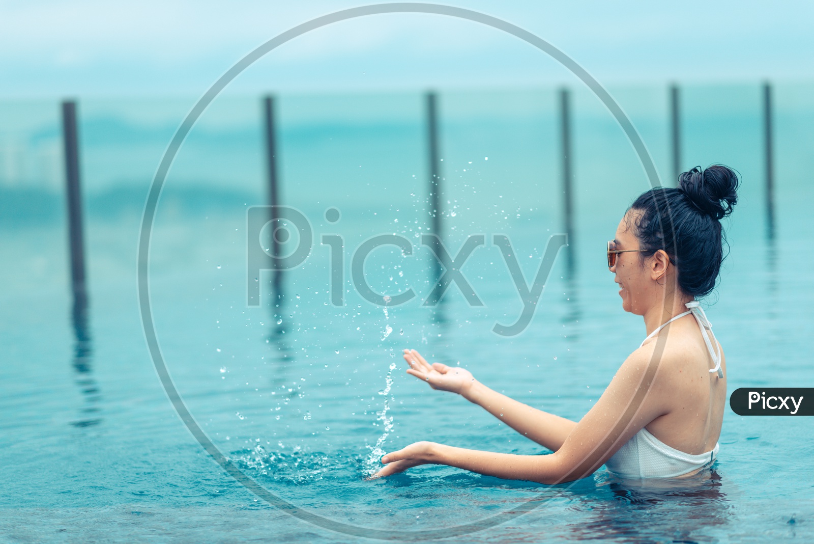 An Asian girl playing with water in Swimming pool on roof top with beautiful city view