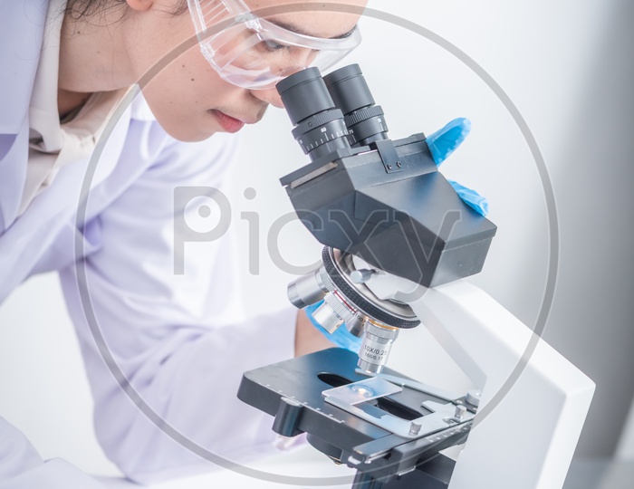 Young Asian  Student Using  Microscope Closeup In a Lab