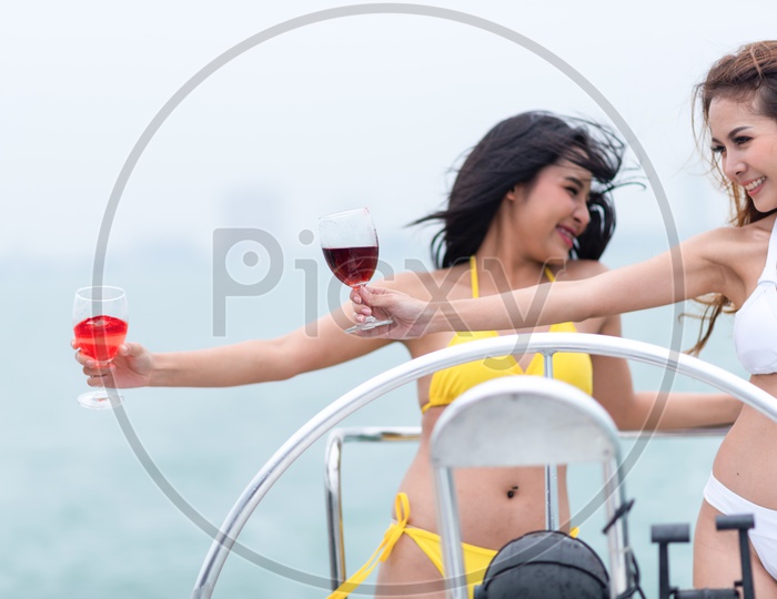 Asian girls in bikini Celebrating the summer with wine in a glass on a yacht