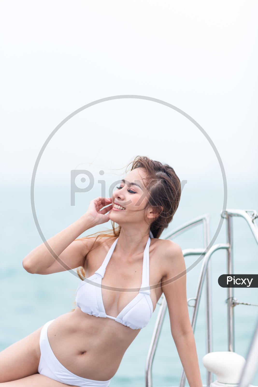Sexy Asian girl in bikini adjusting her hair on a yacht