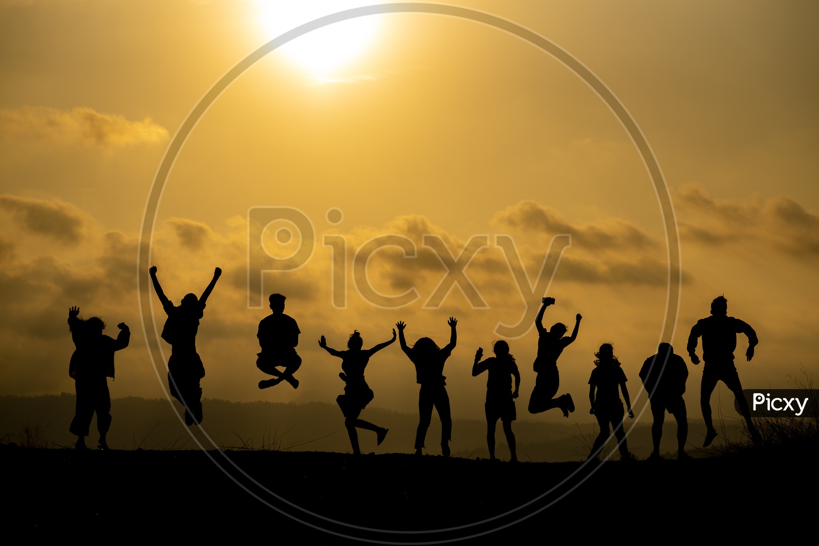 The silhouette of a group of people Jumping in joy Over Sunset Sky
