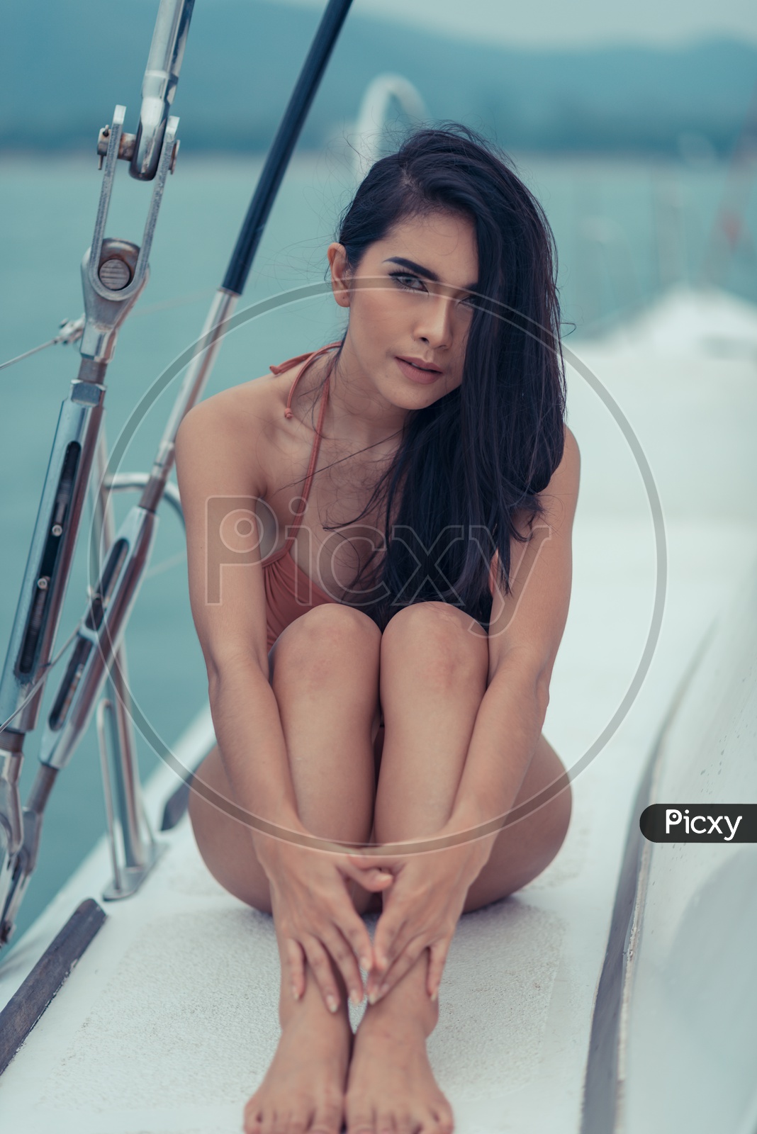 A fashion outdoor summer photoshoot of sexy girl with dark hair in luxurious bikini relaxing on yacht