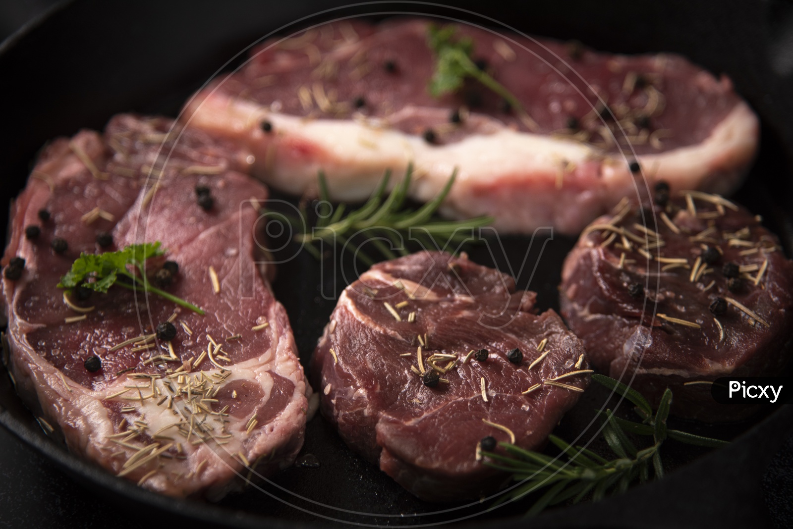 raw beef steaks With Spices Topped On a Cooking Pan Background