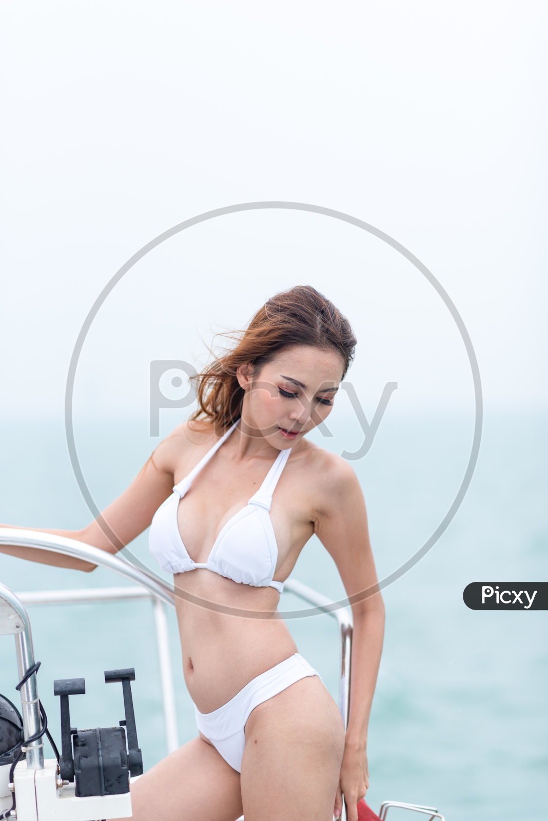 Sexy Asian girl in luxurious white bikini on a yacht