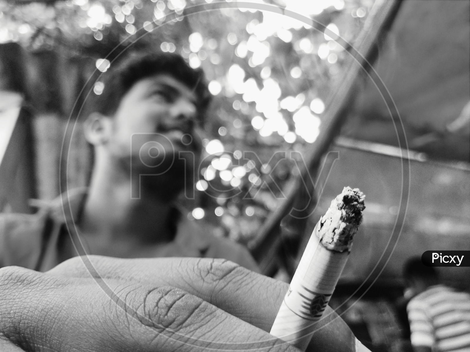 A boy holding cigarette in between his fingers