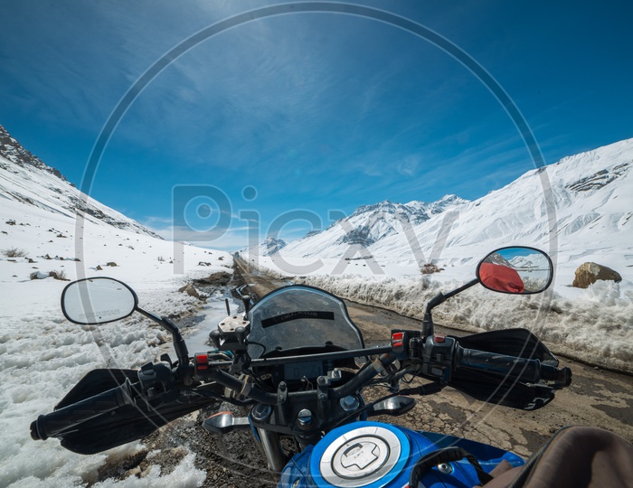 Biker at Snow Covered Road in Spiti Valley with Himalayas Mountains in Snow