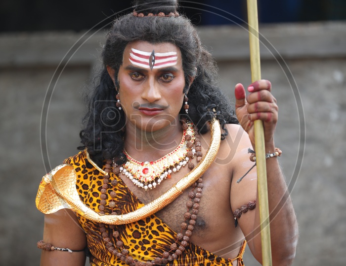 Indian Man dressed up as Lord Shiva having tea