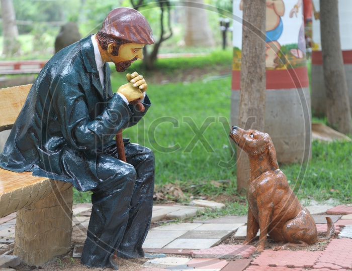 A Man with a Dog Statue In a Lawn Park