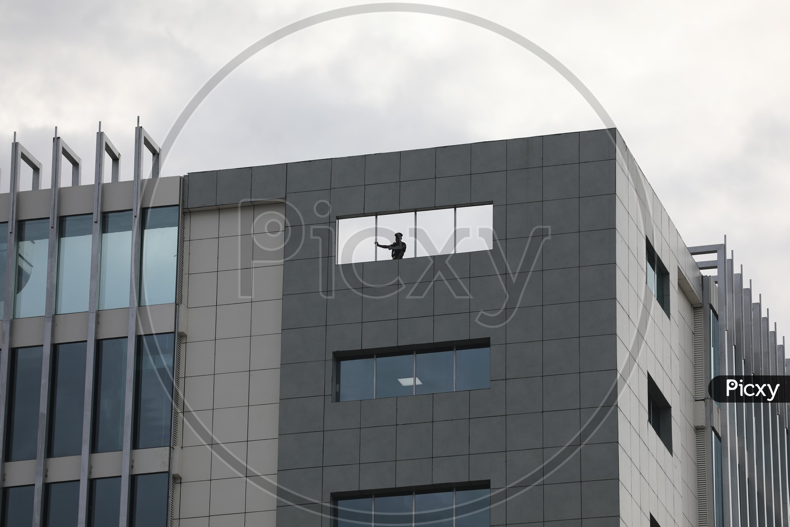 Facade of a Corporate Building With Silhouette Of Security Guard On Top of The Building