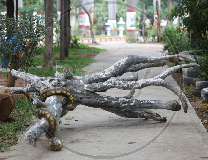 Python Snake Curled to a Wooden Log  Statue in a park